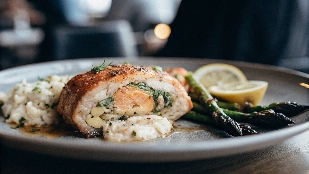 Crab-stuffed salmon fillet with golden-brown edges, garnished with fresh herbs and served alongside roasted asparagus and garlic mashed potatoes.